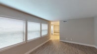 This single-floor residence offers a clean, contemporary design highlighted by consistent neutral tones, white trim, and wood-look flooring throughout the main living areas. The open living room receives generous natural light through a bank of large windows fitted with white horizontal blinds, creating a bright and welcoming atmosphere that flows seamlessly toward additional living or dining space.

The kitchen is well-equipped with white shaker-style cabinetry, granite-look countertops, a stainless steel sink, and a full suite of stainless steel appliances including a gas range, microwave, dishwasher, and refrigerator. Ample upper and lower cabinet storage makes this kitchen both functional and visually cohesive.

The bedrooms feature soft carpeting and are served by dedicated closet space, including a walk-in closet with built-in shelving and rods in the primary bedroom. The primary bathroom includes a granite-topped vanity, wood-look flooring, and access to a separate bathing area. A secondary full bathroom offers subway-tiled shower walls over a soaking tub, a granite vanity, and matching flooring, maintaining the unit's clean, uniform aesthetic throughout.