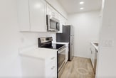 Located at 2601 E McKellips Rd in Mesa, AZ, this 510-square-foot, one-bedroom, one-bathroom unit is designed for efficient, comfortable living across a single floor. Light wood-look flooring runs throughout the entire unit, creating a cohesive and easy-to-maintain aesthetic.

The combined kitchen and living room serves as the heart of the unit. The living area features a ceiling fan with light fixture and a sliding glass door that opens to an outdoor patio, filling the space with natural light and providing views of landscaped greenery. The galley-style kitchen is outfitted with white shaker cabinetry, white quartz countertops, and a full suite of stainless steel appliances, including a refrigerator, electric range, over-the-range microwave, and dishwasher.

The primary bedroom measures 130 square feet and includes a ceiling fan, a large window for natural light, and access to a dedicated closet. The full bathroom features a white vanity with a mirrored medicine cabinet, a full-size soaking tub with shower, and clean white finishes throughout. A hallway connects the main living areas to the bedroom and bathroom, completing the efficient floor plan of this well-appointed Mesa residence.