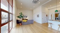 Located at 1525 N American St in Philadelphia, PA, this contemporary two-story home offers 2 bedrooms and 2 bathrooms across two thoughtfully designed floors. The ground floor opens into a spacious combined kitchen and living area bathed in natural light from a striking floor-to-ceiling red-framed window wall that frames street views and floods the space with daylight. Light oak hardwood flooring runs throughout, complementing the crisp white walls and soaring ceilings. The modern kitchen features flat-front cabinetry in a warm taupe finish, stainless steel appliances including a double oven and French-door refrigerator, a generous island with a concrete-style countertop, and pendant lighting in sage green — ideal for both cooking and casual dining. The living area is open and airy, benefiting from recessed lighting and a ceiling-mounted HVAC unit. The upper floor houses the two bedrooms, including a well-proportioned primary bedroom with clean white walls and light hardwood flooring. Two full bathrooms serve the home: one features a glass-enclosed walk-in shower with warm-toned tile and a floating wood vanity, while the second offers a full soaking tub with two-tone tile surround. Hallways connect the upper-level spaces efficiently, completing a well-organized and stylish layout.