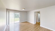 Located at 6200 Hightower Rd in Portsmouth, VA, this single-floor, 2-bedroom, 1-bathroom home offers a clean, modern aesthetic with a thoughtful layout. Light wood-style flooring runs throughout the entire residence, creating a cohesive and bright atmosphere across every room.

The living room is an open, inviting space featuring a window that brings in natural light and provides views of the surrounding greenery. A front entry door opens directly into this area, making it a welcoming focal point of the home.

The kitchen is efficiently designed with white shaker-style cabinetry, granite-look countertops, a stainless steel gas range with an overhead vent hood, and a window above the counter that fills the space with natural light.

The primary bedroom is generously sized, featuring sliding glass doors that open to the outdoors, offering both light and convenient exterior access. A hallway connects the bedrooms and leads to shared living spaces. The second bedroom includes a closet and a window with outdoor views, while an additional bedroom provides a quiet, neutral retreat. Both rooms feature built-in closet storage.

The bathroom includes a full tub-shower combination with clean white tile surround. A central hallway ties all rooms together, completing this functional and comfortable home.