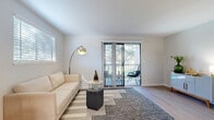 This well-appointed two-story residence offers a clean, contemporary aesthetic throughout its thoughtfully designed layout. The main living area is bright and airy, featuring light hardwood-style flooring, neutral walls, and large sliding glass doors that open onto a private balcony overlooking mature trees — bringing abundant natural light and a serene outdoor connection into the space. Multiple windows fitted with horizontal blinds ensure excellent light control throughout.

The kitchen is a standout feature, showcasing a striking two-tone design with bold navy lower cabinetry paired with crisp white upper cabinets and light quartz countertops. Stainless steel appliances, including a range, dishwasher, and refrigerator, complete this functional and stylish space.

The bedrooms offer a comfortable retreat, with plush carpet flooring, generous windows that invite natural light, and sliding closet storage. The bathrooms echo the kitchen's design language, featuring navy vanity cabinetry, white quartz countertops, brushed nickel fixtures, and large mirrors that amplify the sense of space. One bathroom includes light wood-style flooring, while another presents a more intimate layout with elegant pendant lighting. Overall, the residence presents a cohesive, modern palette with refined finishes throughout.