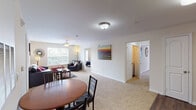 This single-floor residence offers a well-organized layout that balances communal living spaces with private retreats. The open-concept living and dining area forms the heart of the unit, where soft carpet flooring, ceiling fans, and natural light from multiple windows create a comfortable and inviting atmosphere. A round dining table sits adjacent to the living room, which provides ample space for seating and relaxation.

The kitchen is efficiently designed with warm oak cabinetry extending to the upper walls, providing generous storage. Black appliances, including an electric range, over-the-range microwave, dishwasher, and refrigerator, are paired with light countertops and a single-basin sink. Wood-style flooring runs throughout the kitchen, adding a practical, durable surface.

The unit includes multiple bedrooms, each carpeted and equipped with ceiling fans. The bedrooms receive natural light through windows with views of surrounding greenery. Two bathrooms serve the unit, each featuring a tub-shower combination, wood-style flooring, and oak vanity cabinetry. The overall design is clean and neutral, offering a functional and comfortable living environment throughout.