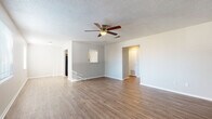 Located at 1606 Jackson St in Fort Smith, Arkansas, this single-story home offers a practical and well-organized layout throughout. The living area is a welcoming, open space featuring light wood-look flooring, a ceiling fan with integrated lighting, and a textured ceiling. A bold teal accent wall adds a pop of color, while a window allows natural light to fill the room. An arched pass-through connects the living space to adjacent areas, enhancing the open feel of the floor plan. The galley-style kitchen is efficiently designed with white cabinetry, gray countertops, and wood-look flooring that continues from the main living area. It is equipped with black appliances including a refrigerator, gas range, and dishwasher, along with a double-basin sink beneath upper cabinetry. The bedrooms feature neutral carpet, soft gray walls, and generously sized closets with rod storage. Natural light enters through windows fitted with blinds. The bathroom includes white cabinetry with gray countertops, a single-basin sink, and a large mirror, with wood-look flooring carrying through the hallway. Clean lines, neutral tones, and consistent finishes throughout give this home a cohesive and move-in-ready appeal.