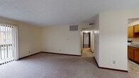 This single-floor unit at 64 Gahl Terr in Reading, Ohio offers a practical and well-organized layout designed for comfortable everyday living. The living area is generously proportioned, finished with neutral-toned carpet and cream-colored walls that create a bright, open atmosphere. A sliding glass door with vertical blinds fills the space with natural light while providing access to an outdoor area, making it a welcoming central gathering space. The kitchen is equipped with warm oak-toned cabinetry offering ample storage, gray laminate countertops, a white electric range, dishwasher, and a double-basin sink. The tile flooring adds durability and easy maintenance to this functional cooking space. A hallway connects the main living area to the private quarters, which include multiple carpeted bedrooms, each featuring textured ceilings, neutral walls, and windows with blinds that allow for natural light and privacy. Dark wood baseboards provide a consistent design detail throughout the unit. The bathroom is cleanly appointed with a wood-toned vanity, white countertop, a tub-shower combination with tiled surround, and matching tile flooring. Overall, the unit presents a clean, functional, and move-in ready environment suited for a range of occupants.
