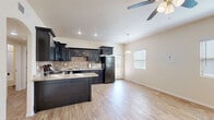 Located in Horizon City, Texas, this single-story, 2-bedroom, 1-bathroom home offers a practical and well-appointed layout suited for comfortable everyday living. The open-concept main area seamlessly connects the kitchen, dining, and living spaces, creating a bright and functional hub of the home. The kitchen is a standout feature, showcasing bold dark cabinetry with raised-panel detailing, a tile backsplash, granite-look countertops, and a peninsula that adds additional prep and seating space. Wood-look flooring flows throughout the main living area, complemented by recessed lighting, a ceiling fan, and a pendant light over the dining space. Natural light filters in through several windows and a glass exterior door, offering views to the outdoors. Both bedrooms are carpeted and feature neutral walls, windows with blinds, and closet access — the primary bedroom includes a walk-in closet. The shared full bathroom is outfitted with a dark-framed vanity with granite-look countertop, a large mirror, and a tub-shower combination. Three closets throughout the home provide ample storage. A connecting hallway ties the private sleeping quarters to the main living area, completing this efficient and thoughtfully designed floor plan.