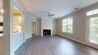Located on Wendwood Lane in Charlotte's 28211 zip code, this single-floor residence offers a thoughtfully designed layout spread across several well-appointed rooms. The living room serves as the central gathering space, featuring elegant crown molding, a classic fireplace with a white surround, durable wood-look flooring in a cool gray tone, and a ceiling fan overhead. Large windows and a set of French doors flood the room with natural light and provide views of surrounding greenery, creating a bright and welcoming atmosphere.

The kitchen is outfitted with white shaker-style cabinetry, light quartz countertops, a subway tile backsplash, and a full suite of stainless steel appliances including a gas range, over-the-range microwave, and refrigerator. Wood-look flooring continues throughout this space for a cohesive aesthetic.

Multiple bedrooms feature neutral carpet, ceiling fans, and windows offering natural light and outdoor views. The primary bathroom includes a soaking tub, a white vanity with quartz countertop, wood-look flooring, and access to a walk-in closet. A second full bathroom mirrors the clean, neutral palette with a tiled tub-shower combination and a white vanity.
