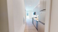 Located at 1529 N Fremont Street in Chicago's Lincoln Park neighborhood, this thoughtfully designed single-floor unit offers an efficient and contemporary living space. The layout consists of a combined kitchen and living room, a full bathroom, and a connecting hallway — each finished with a clean, modern aesthetic throughout.

The kitchen features sleek, flat-front cabinetry in a soft neutral tone, extending from floor to ceiling to maximize storage. Stainless steel appliances, a white quartz countertop, and an under-mount sink complete the functional and polished cooking area. Light wood flooring runs continuously through the space, lending warmth and visual continuity.

The living area is bright and open, benefiting from large floor-to-ceiling windows and a sliding glass door that leads directly to a private balcony. Abundant natural light fills the room, offering views of the surrounding courtyard and neighboring contemporary architecture. A wall-mounted mini-split system provides efficient climate control.

The bathroom showcases a bold design statement with full-surround checkerboard tiling in sage green and white, complemented by matte black hardware and a glass-enclosed walk-in shower with a built-in shelf and lighted mirror. The overall design of this unit balances compact efficiency with distinctive modern finishes, making it a well-appointed space in a prime Chicago location.