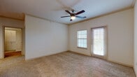 This single-story unit at 12105 SH-151 W in San Antonio, Texas offers a well-organized layout connecting living, kitchen, and bedroom spaces in a functional flow. The living area is generously sized, finished with wall-to-wall carpet, crown molding, and a ceiling fan with a light fixture. Natural light enters through a large window and a glass-paneled exterior door fitted with blinds, providing both brightness and outdoor access.

The kitchen is designed with a pass-through opening overlooking the living space, creating an open and connected feel. It features warm wood cabinetry, granite-style countertops, wood-look flooring, and stainless steel appliances including a refrigerator, electric range, and built-in microwave. Pendant lighting and track lighting illuminate the kitchen and adjacent areas effectively.

The bedrooms are carpeted and receive natural light through windows with blinds. Ceiling fans are present, and the rooms offer comfortable proportions with access to the hallway. The bathroom is well-appointed with a dual-sink vanity featuring dark cabinetry and granite countertops, a tub-shower combination with tile surround, and wood-look flooring, giving the space a cohesive and practical finish throughout.