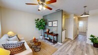 This efficiently designed one-bedroom, one-bathroom single-story residence offers a thoughtful layout across five distinct spaces, including a living room, kitchen, bedroom, bathroom, and closet. The living room serves as the heart of the home, showcasing light wood-look flooring, a textured ceiling with a ceiling fan and light fixture, and a distinctive sage green accent wall that adds a touch of character. Natural light filters through sheer curtains, creating a bright and welcoming ambiance. The kitchen is well-equipped with gray shaker-style cabinetry, white countertops, a stone tile backsplash, and standard appliances including a range and dishwasher — offering an efficient and clean workspace. The bedroom provides a comfortable retreat, featuring plush carpeting, a ceiling fan, and a generous window dressed with sheer curtains that invite soft natural light. A dedicated closet adds practical storage. The bathroom includes a vanity with white cabinetry, a solid countertop, and a large mirror. Throughout the residence, a neutral color palette and consistent design choices create a cohesive and inviting atmosphere well-suited for comfortable everyday living.