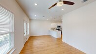 Located at 2009 S Veterans Blvd in Gonzales, Louisiana, this single-story home offers a thoughtfully designed open-concept layout with clean, modern finishes. Light wood-tone flooring runs throughout, complementing the crisp white walls and creating a bright, cohesive aesthetic.

The living area flows seamlessly into the kitchen and dining space, with a ceiling fan overhead and natural light streaming through windows and a glass-panel front door. The kitchen is a standout feature, boasting white shaker-style cabinetry, a grey subway tile backsplash, a white quartz peninsula with double sink, pendant lighting, and stainless steel appliances including a refrigerator, microwave, and range.

The spacious primary bedroom includes a ceiling fan, a window with outdoor views, and a closet. The en suite bathroom features a white vanity with quartz countertop, a glass-enclosed shower, and matte black fixtures. The second bedroom is similarly appointed with a ceiling fan and natural light, while the second full bathroom offers a tub-shower combo with dark bronze hardware and a matching vanity.

A dedicated laundry room with washer and dryer hookups includes a rear glass-panel door leading to the backyard. The layout also includes a hallway and additional closet space, rounding out a functional and well-finished home.