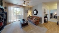This single-floor residence offers a thoughtfully designed layout that balances comfort and functionality across its key living spaces. The kitchen serves as a central highlight, featuring rich wood cabinetry extending to the upper walls, granite countertops, black appliances including a range and built-in microwave, and a large island with bar seating and an integrated sink. Light hardwood flooring flows through the kitchen and dining area, which is illuminated by a skylight and track lighting. A dedicated in-unit laundry area with a full-size washer and dryer is conveniently located just off the kitchen. The living room is bright and welcoming, with plush carpeting, a ceiling fan, and large sliding glass doors that open to an outdoor space and allow for generous natural light and views of surrounding greenery. Two bedrooms are carpeted and well-proportioned, each offering windows with natural light. Both bathrooms are finished with tile flooring, warm wood vanities, dark countertops, and full soaking tub-shower combinations with curtain rods. The overall aesthetic is warm and cohesive, with neutral tones and consistent finishes throughout that create an inviting and comfortable living environment.