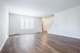 This two-story home in Madison, Wisconsin offers a thoughtfully arranged layout spread across two well-proportioned floors. The main level features an open living room with rich hardwood-style flooring, a ceiling fan, and natural light streaming through a front-facing window. The adjacent kitchen is equipped with dark espresso-toned cabinetry, light stone-finish countertops, a double stainless steel sink, and stainless steel appliances including a refrigerator and dishwasher. A hallway and staircase with carpeted treads and a clean white railing connect the floors. Three hallways provide smooth circulation throughout the home. The upper level hosts both bedrooms, each finished with soft wall-to-wall carpeting, closets with hanging rods, and windows fitted with blinds for privacy. The spacious primary bedroom offers generous room and ample closet storage. Three bathrooms serve the home, including one featuring a soaking tub with marble-style surround, a wood-toned vanity, and hardwood-style flooring. Additional bathrooms maintain a clean, minimalist aesthetic with white countertops and framed mirrors. A dedicated closet adds further storage convenience to this well-organized home.
