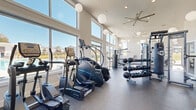 Located at 888 Horizon Boulevard in Athens, Georgia, this single-floor fitness center is a well-appointed facility designed to support a comprehensive workout experience. The space is characterized by soaring ceilings and expansive floor-to-ceiling windows that flood the interior with abundant natural light while offering unobstructed views of the outdoor pool area, creating an energizing and open atmosphere throughout.

The facility is organized into distinct functional zones. The cardio area lines the window wall and is equipped with a row of TRUE-brand treadmills, ellipticals, and stair climbers, allowing users to exercise while enjoying the outdoor scenery. A dedicated strength training section features a multi-station cable machine, a full dumbbell rack ranging across multiple weight increments, kettlebells, and a heavy punching bag, catering to a wide range of free-weight and functional training needs.

A separate, enclosed room provides space for additional equipment including rowing machines, air bikes, and benches, offering a more focused training environment. Plate-loaded cable machines and selectorized strength machines round out the resistance training options. Rubber flooring throughout ensures safety and durability across all workout zones.

The interior design is clean and contemporary, with crisp white walls, globe pendant lighting, and a ceiling fan. A wall-mounted television and exercise ball storage add further utility. Direct glass door access to the pool deck seamlessly connects the indoor and outdoor amenity spaces.