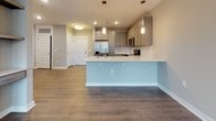 Located at 50 Central Island Street on the sought-after Daniel Island in South Carolina, this single-floor residence offers a thoughtfully designed layout with contemporary finishes throughout. The open-concept living and kitchen area serves as the heart of the home, where wood-look luxury vinyl plank flooring extends seamlessly across the space. The kitchen is well-appointed with gray shaker-style cabinetry, a classic white subway tile backsplash, and a full suite of stainless steel appliances, including a French door refrigerator, electric range with over-the-range microwave, and dishwasher. A peninsula island with a white quartz countertop and undermount sink provides additional prep space and casual seating, accented by elegant pendant lighting overhead. The bathroom is finished with a granite-topped vanity, white shaker cabinetry, a large framed mirror, and a full tub-shower combination with large-format gray tile surround. The bedroom features plush wall-to-wall carpeting, soft neutral gray walls, a ceiling fan, and a window with blinds that allows natural light to filter in. A stacked laundry unit is conveniently located within the unit, as visible in the floor plan view. The overall aesthetic is clean, modern, and move-in ready.