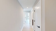 This contemporary high-rise unit is thoughtfully designed with a clean, modern aesthetic throughout. Light-toned hardwood flooring flows seamlessly across all living areas, complementing the bright, neutral color palette of the walls and trim.

The open-concept kitchen is a standout feature, showcasing a large waterfall-edge island with an undermount sink, warm wood-grain cabinetry, a subway tile backsplash, and a full suite of stainless steel appliances. A floor-to-ceiling glass door connects the kitchen directly to a balcony, inviting abundant natural light and outdoor views.

The living and bedroom areas benefit from expansive floor-to-ceiling windows with sleek black frames, offering sweeping panoramic views of the surrounding cityscape, highways, and greenery below — a defining characteristic of this elevated unit.

A clean, well-lit hallway with recessed lighting and matte black hardware connects the private spaces of the unit. Two bathrooms provide functional elegance: one features a soaking tub with large-format tile surround, a wood-toned vanity with white countertop, and access to a walk-in closet; the second offers a streamlined single-vanity design with matching finishes and tile flooring. Together, the spaces present a cohesive, move-in-ready environment with a polished, contemporary feel.