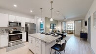 Located at 101 Zora Place in Lockhart, FL, this single-floor residence offers a thoughtfully designed 2-bedroom, 2-bathroom layout that maximizes both comfort and functionality. The open-concept kitchen and living area serves as the heart of the home, anchored by a granite-topped kitchen island with bar seating for four. White shaker cabinetry, stainless steel appliances, pendant lighting, and light wood-style flooring give the kitchen a clean, contemporary feel. The living area flows naturally from the kitchen, featuring sage green accent walls, a ceiling fan, and access to an additional den or flex room through sliding glass doors — ideal as a home office or sunroom. Both bedrooms feature plush carpeting, multiple windows with natural light, ceiling fans, and ample closet space across three closets total. The primary bedroom offers a generous footprint with outdoor views. The two bathrooms are finished with granite vanities and white cabinetry; one includes a walk-in shower with glass enclosure. A dedicated laundry room with full-size washer and dryer connections adds everyday convenience. The overall ambiance is bright, modern, and move-in ready.