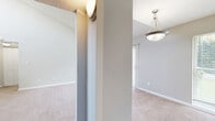 This one-bedroom, one-bathroom unit at 260 Northern Ave in Avondale Estates, Georgia offers a thoughtfully laid-out single-floor plan. The living room is an immediate highlight, featuring soaring vaulted ceilings that create an open, airy atmosphere, soft neutral-toned carpet, and a sliding glass door framed by vertical blinds that floods the space with natural light and provides access to outdoor views. A pendant light fixture marks the transition from the carpeted living area to the hard-surface entryway and kitchen zone. The kitchen is efficiently designed with dark espresso cabinetry, granite-style countertops, wood-look flooring, and black appliances including an electric range. The bedroom is a generously sized retreat with plush carpeting, a textured ceiling, and a window allowing in natural light. Two closets provide ample storage throughout the unit. The bathroom is well-finished, featuring a dark-vanity with granite-style countertop, a framed mirror, wood-look flooring, and a tub/shower combination with full-height earth-toned tile surround. An open shelving unit adjacent to the vanity offers additional storage. Neutral wall tones and consistent finishes throughout the unit create a cohesive and comfortable living environment.