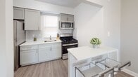 This single-floor residence at Browning On in Brooklawn, NJ offers a thoughtfully designed layout with a clean, modern aesthetic throughout. The living room serves as a bright, welcoming central space, featuring wood-style flooring, neutral gray walls, and large windows that allow generous natural light to fill the room.

The kitchen is well-appointed with gray shaker-style cabinetry, light quartz countertops, a subway tile backsplash, and stainless steel appliances including a gas range and over-the-range microwave. A peninsula with bar seating connects the kitchen to the adjacent dining area, creating a practical and sociable open-concept flow.

The unit includes multiple bedrooms, each finished with neutral gray walls, plush carpeting, and windows providing natural light. The primary bedroom offers ample space, while a secondary bedroom provides a cozy, functional layout suitable for a variety of uses.

The bathroom features a full soaking tub with an overhead shower, framed by floor-to-ceiling large-format neutral tile in warm beige tones and brushed nickel fixtures, lending a clean and contemporary feel.

Overall, the space presents a cohesive, understated palette of whites, grays, and warm wood tones, creating a comfortable and functional living environment.