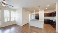 Located at 1475 Gears Rd in Houston, TX, this one-bedroom, one-bathroom unit offers a well-designed single-floor layout that makes efficient use of its space. The open-concept living and kitchen area is anchored by rich, dark-stained cabinetry paired with granite countertops and a peninsula island with pendant lighting overhead. Black appliances, a subway tile backsplash, and wood-style flooring complete the kitchen's polished look. The living area flows naturally from the kitchen, featuring neutral walls, a large window for natural light, and hardwood-style flooring throughout.

The bedroom is generously sized, finished with plush carpet, a ceiling fan, and dual windows with blinds that invite ample natural light and outdoor views. Double doors open into a large walk-in closet outfitted with wire shelving systems along multiple walls, providing extensive storage capacity.

The bathroom features wood-style flooring, a granite-topped vanity with a dark wood cabinet base, and a full tub-shower combination with white tile surround and chrome fixtures. The clean, neutral palette throughout the unit creates a cohesive and functional living environment suited for everyday comfort.