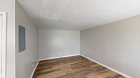 Located at 1800 Augusta Ct in Lexington, Kentucky, this single-story 3-bedroom, 1-bathroom home offers a functional and well-maintained layout. Throughout the home, wood-look plank flooring in warm tones provides a consistent, clean aesthetic, complemented by neutral gray walls and crisp white baseboards.

The living room greets you at the entrance, featuring a textured ceiling, a front-facing window with blinds for natural light, and direct access to the main entry door. The kitchen is a standout feature, boasting white shaker-style cabinetry, granite-look countertops, stainless steel appliances including a refrigerator, and a black electric range with overhead ventilation.

The three bedrooms each carry the same wood-look flooring and neutral color palette. The primary bedroom offers a comfortable footprint, while the additional bedrooms feature windows with blinds that allow natural light. Textured ceilings are consistent throughout the bedrooms.

The full bathroom includes a tub-shower combination with a white surround, a white vanity with a single sink, a mirror, and wood-look flooring. A dedicated utility room rounds out the floor plan. Overall, the home presents a clean, move-in ready interior with consistent finishes throughout.