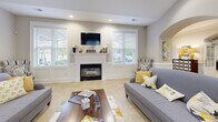 Located at 100 Avalon Park Cir in Asheville, NC, this single-floor community space offers a generously sized, open-concept layout designed for comfortable gathering and socializing. The interior is defined by elegant arched doorways and passageways that lend a refined architectural character throughout.

The main living area features a classic fireplace framed by a white mantel and flanked by large windows fitted with horizontal blinds, allowing ample natural light to fill the space. Recessed lighting and vaulted ceilings in select areas add to the sense of openness and airiness. Light-toned ceramic tile flooring flows seamlessly throughout, enhancing the bright, welcoming ambiance.

A well-appointed kitchen area includes rich cherry wood cabinetry, granite countertops, black appliances, and a curved breakfast bar with seating. Pendant lights hang above the bar, adding a stylish focal point. A dedicated dining area with seating for multiple guests sits adjacent, making the space highly functional for group use.

The layout also incorporates a reception-style counter framed by a prominent arched surround, adding a polished, professional touch. Overall, the space presents a clean, neutral palette accented with warm wood tones, offering a versatile and inviting environment.