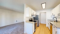 This 760 square foot apartment offers a well-designed living space with two bedrooms and one bathroom. The interior showcases a blend of modern finishes and practical features. The kitchen, a highlight of the home, boasts a galley-style layout with white cabinetry, light-colored countertops, and stainless steel appliances. The light wood-look flooring in the kitchen contrasts nicely with the neutral-toned carpet found in the living areas and bedrooms.

The primary bedroom, measuring 160 square feet, provides a cozy retreat with a large window allowing natural light to flood the space. Both bedrooms feature sliding closet doors, offering ample storage. The bathroom, while compact, is efficiently designed with a single vanity, toilet, and shower/tub combination.

The living area is brightened by a sliding glass door leading to an outdoor space, likely a balcony or patio. Throughout the apartment, textured ceilings add character, while the predominantly white walls create a sense of openness. The overall layout, as seen in the 3D floor plan, shows a thoughtful arrangement of rooms that maximizes the available space in this single-story dwelling.