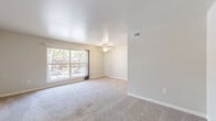 Located at 117 Olde Jamestowne Ct in Williamsburg, Virginia, this one-bedroom, one-bathroom home offers a well-organized, single-floor layout designed for comfortable everyday living. The living room serves as the heart of the home, featuring plush wall-to-wall carpeting, a ceiling fan, and a large picture window that fills the space with natural light and provides views of the surrounding neighborhood and mature trees. Neutral, warm-toned walls throughout create a clean and welcoming ambiance. The bedroom is a comfortable retreat, also finished with soft carpeting and neutral walls, offering direct access to a hallway with multiple closets — four in total — providing exceptional storage throughout the home. The galley-style kitchen is efficiently appointed with rich dark-stained cabinetry, light granite-look countertops, white appliances including an electric range and full-size refrigerator, and durable tile flooring. A combined dining and kitchen area allows for flexible use of the space. The bathroom features a full-size soaking tub and shower combination with a clean, all-white surround. A connecting hallway ties all rooms together seamlessly. The home's straightforward layout and abundant closet space make it a practical and inviting residence.