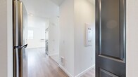 Located in Post Falls, Idaho, this thoughtfully designed unit offers a clean, modern aesthetic across a single floor. Light wood-style flooring flows seamlessly throughout the space, complementing the crisp white walls and creating a bright, cohesive atmosphere.

The living room is a standout feature, boasting tall ceilings and a wall of large black-framed windows paired with a glass-paneled door that opens to a balcony. This corner placement floods the room with natural light and frames sweeping views of the surrounding landscape, including distant mountains and open skies.

The kitchen is well-appointed with rich, dark-toned cabinetry, light countertops, and a full suite of stainless steel appliances including a refrigerator, electric range, microwave, and dishwasher. A built-in range hood adds a polished, functional touch, while the galley-style layout maximizes efficiency.

The bathroom is clean and minimalist, featuring a tub-shower combination, a natural light-admitting window, and chrome fixtures against all-white surroundings.

A dedicated in-unit laundry area includes a full-size top-load washer and dryer, providing added everyday convenience. The entryway, featuring a dark-toned front door and utility panel, leads smoothly into the main living spaces, making this unit as practical as it is visually appealing.