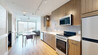 Located at 6919 Main St in Houston's Texas Medical Center district, this modern 2-bedroom, 2-bathroom unit offers a thoughtfully designed open-concept layout with consistent light wood flooring throughout. The combined kitchen and living area forms the heart of the space, showcasing a sleek galley-style kitchen outfitted with wood-grain cabinetry, white quartz countertops, a subway tile backsplash, and a full suite of stainless steel appliances including a range, microwave, dishwasher, and refrigerator. Track lighting and a pendant light illuminate the kitchen, which flows naturally into the dining and living areas. Expansive floor-to-ceiling windows flood the living room with natural light and frame striking panoramic views of the Houston skyline. Both bedrooms continue the floor-to-ceiling window theme, offering impressive city vistas and a bright, airy atmosphere. Each bedroom is served by its own closet, providing generous storage. The two bathrooms feature wood-tone floating vanities, quartz countertops, and clean white tile work, with the primary bathroom including a full soaking tub and shower. An in-unit laundry area adds everyday convenience to this well-appointed urban residence.