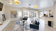 Located at 9200 N Normandale St in Fort Worth, TX, this single-floor space offers a well-designed open-concept layout that seamlessly integrates the kitchen and living areas. The living room is anchored by a white brick fireplace with a mounted television above the mantle, creating a welcoming focal point. Light hardwood-style flooring runs throughout, complementing the neutral, warm color palette of the walls and trim. Large windows along the perimeter flood the space with abundant natural light and provide views of the surrounding outdoor environment, enhancing the bright and airy ambiance. Elegant yellow drum pendant lights add a cheerful pop of color to the ceiling. The kitchen features a peninsula with a light countertop and bar seating, ideal for casual dining or workspace use, alongside stainless steel appliances including a French door refrigerator. A set of French doors with glass panels connects the interior to an adjacent area, adding architectural charm and continuity. The space also includes a dedicated dining nook positioned near the windows, making it a versatile and functional area. Overall, the design balances contemporary style with comfortable, practical living elements throughout.