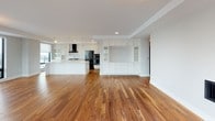 This two-bedroom, two-and-a-half-bath penthouse delivers an expansive, single-floor layout designed with upscale finishes and thoughtful functionality. The open-concept living and kitchen area is anchored by rich hardwood flooring that flows throughout the residence, creating a warm and cohesive aesthetic. A built-in cabinetry wall with glass-front displays adds architectural interest to the main living space.

The gourmet kitchen is outfitted with white shaker cabinetry extending to the ceiling, a striking stone-topped island with waterfall-edge detailing, a gas cooktop beneath a sleek stainless steel range hood, black stainless appliances, and under-cabinet lighting. A dedicated laundry area provides a side-by-side washer and dryer with overhead cabinetry and a stone countertop for added convenience.

The primary bath features marble-look tile flooring, a soaking tub with tiled surround, a glass-enclosed walk-in shower, and an extended white vanity. Both bedrooms include generously sized walk-in closets with custom white shelving systems, built-in drawers, hanging rods, and dedicated hook rails. A half bath serves the common areas. Natural light enters through large windows, and ceiling fans add comfort to the bedrooms.