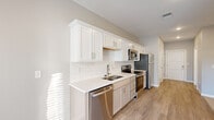 Located at 2620 W Sunshine St in Springfield, Missouri, this efficiently designed single-floor unit offers a well-appointed living space with modern finishes and a functional layout. The open-concept interior features light-toned luxury vinyl plank flooring that flows seamlessly throughout the main living and kitchen areas, transitioning to plush carpet in the living zone.

The kitchen is a standout feature, showcasing crisp white shaker-style cabinetry with brushed nickel hardware, a classic white subway tile backsplash, and light quartz countertops. A full suite of stainless steel appliances — including a refrigerator, range, built-in microwave, and dishwasher — provides everything needed for everyday cooking and entertaining.

The living area is bright and open, illuminated by recessed lighting and a ceiling fan, with a set of glass French doors that invite natural light and provide access to the exterior. The bathroom is clean and contemporary, featuring large-format tile flooring, a glass-enclosed shower, and chrome fixtures throughout.

Neutral gray wall tones, crisp white trim, and consistent modern finishes create a cohesive, move-in-ready aesthetic. The unit also includes an accessible electrical panel and ample storage. Situated in a convenient Springfield location with on-site parking, this unit is an ideal low-maintenance living space.