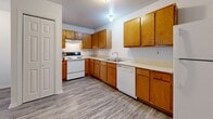 Located at 1501 S Main St in Stillwater, Oklahoma, this two-bedroom, one-bathroom unit offers a practical and functional single-floor layout. The open-concept main living area seamlessly combines the living room, dining room, and kitchen, creating a connected and versatile space. The kitchen is equipped with warm oak-toned cabinetry, light countertops, a dishwasher, refrigerator, and electric range, all set atop durable wood-look vinyl flooring. A ceiling fan with light fixture anchors the living area, contributing to a comfortable atmosphere. Both bedrooms feature plush wall-to-wall carpeting and natural light from windows with blinds. The primary bedroom includes access to a dedicated walk-in closet with wire shelving, providing generous storage. The bathroom is finished with vinyl plank flooring, oak cabinetry, and accessibility grab bars. Additional conveniences include a dedicated laundry room, a pantry, a utility room, and a second closet. Clean white walls and neutral finishes throughout create a bright, move-in-ready environment well-suited for a variety of living arrangements.