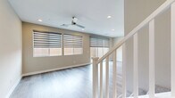This two-story home offers a thoughtfully designed layout across two floors, with the main level providing a more compact, functional footprint and the upper level delivering generous living space. The open-concept kitchen and living room on the main floor serves as the heart of the home, featuring dark espresso cabinetry, stainless steel appliances including a gas range, microwave, and French door refrigerator, quartz countertops, and a classic subway tile backsplash. A convenient half bath with a pedestal sink is also located on the main level. Light wood-look flooring flows throughout both floors, complementing the neutral warm-toned walls and crisp white trim. The living area is bright and airy, with multiple windows dressed in layered roller shades and a ceiling fan overhead. Sliding glass doors provide direct access to the outdoor patio, allowing natural light to fill the space. Upstairs, four bedrooms offer comfortable accommodations, including a well-proportioned primary suite. Three walk-in style closets provide ample storage. Two dedicated laundry areas add everyday convenience. The bathrooms maintain a clean, modern aesthetic consistent with the rest of the home. Throughout, recessed lighting and a cohesive design palette create a polished, move-in-ready atmosphere.