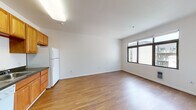 Located at 2312 Fulton St in Berkeley, CA, this single-floor unit offers a clean, functional layout with a cohesive design throughout. Warm hardwood-style flooring runs continuously across all rooms, lending a sense of continuity and ease of movement between spaces.

The open living and dining area is bright and generously proportioned, anchored by a large window that admits ample natural light and provides views of the surrounding neighborhood. White walls and a smooth ceiling keep the space feeling airy and neutral, offering a versatile backdrop for a variety of furnishing styles.

The kitchen is positioned adjacent to the main living area, featuring warm-toned wood cabinetry that extends to the upper walls for abundant storage. Dark granite-style countertops provide contrast, while white appliances—including a refrigerator, dishwasher, range, and microwave—offer full functionality. A stainless steel sink completes the workspace.

A separate bedroom offers a quiet, private retreat with the same hardwood-style flooring and neutral white walls, providing a blank canvas for personalization. The full bathroom is well-appointed with a combined tub and shower enclosed by sliding glass doors, a wood-cabinet vanity with dark countertop, a large mirror, and coordinating hardwood-style flooring.