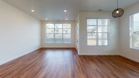 Located at 4411 W Glendon Dr in Lehi, Utah, this two-story home offers a thoughtfully designed layout across two well-appointed floors. The main level showcases an open-concept living and kitchen area finished with warm hardwood-style flooring and recessed lighting throughout. The kitchen is equipped with white shaker cabinetry, light quartz countertops, stainless steel appliances including a gas range, microwave, and refrigerator, complemented by matte black hardware for a modern touch. Large windows in the living area flood the space with natural light and provide views of the surrounding neighborhood. A staircase with sleek metal railings connects the main floor to the upper level. Upstairs, the bedrooms feature vaulted ceilings with ceiling fans and plush carpeting, creating a comfortable retreat. The primary suite includes a spacious walk-in closet with built-in shelving and a private en-suite bathroom complete with a soaking tub, glass-enclosed shower, and a window for natural light. Additional bedrooms are well-sized with ample closet space. A full secondary bathroom with a tub/shower combo, white cabinetry, and light tile flooring serves the remaining rooms. The home's clean, neutral palette and modern finishes create a bright, cohesive atmosphere throughout.