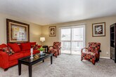 Located at 1136 County Line Rd in Kansas City, KS, this single-floor residence offers a functional and comfortable layout with a cohesive warm, neutral color palette throughout. The living room serves as the heart of the home, featuring plush carpeting, a textured ceiling, and a large sliding glass door that floods the space with natural light and provides access to an outdoor balcony area. The dining area is distinguished by exposed beam detailing on the ceiling and warm hardwood-style flooring, anchored by an elegant chandelier that adds a classic touch. The kitchen is efficiently designed with white cabinetry, ample counter space, and a full suite of white appliances including a refrigerator, electric range, dishwasher, and built-in storage — all complemented by hardwood-style flooring. The bedroom is a quiet, carpeted retreat with a bright window and generous space for furnishings. An additional versatile room with carpet and a window offers flexibility as a home office or secondary bedroom. The bathroom features hardwood-style flooring, a vanity with cabinet storage, and a shower/tub combination. Throughout the residence, neutral wall tones and consistent flooring materials create a unified, welcoming atmosphere.