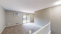 Located at 2845 Englewood Ave SE in Grand Rapids, MI, this two-story home offers a thoughtfully laid-out 1-bedroom, 1-bathroom floor plan spread across two equally sized levels. The main floor hosts an open-concept living, dining, and kitchen area finished with light wood-look flooring throughout. The kitchen is well-appointed with modern light wood cabinetry, white countertops, a double-basin stainless steel sink, and a full suite of stainless steel appliances including a refrigerator, electric range, and over-the-range microwave. The dining area flows naturally from the kitchen, providing a clean, functional space. The living room features plush carpeting, neutral gray walls, a wall-mounted air conditioning unit, and a sliding glass door that opens to an outdoor view, allowing natural light to fill the space. Upstairs, the spacious bedroom is carpeted and features a closet with louvered bifold doors, a window with natural light, and easy access to the full bathroom, which includes a single-sink vanity and a tub/shower combo. Two closets provide additional storage throughout. The lower level features an unfinished basement area with carpeted flooring, offering flexible space for storage or other uses. A staircase with white balusters connects the levels, completing this clean and functional home.