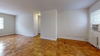 This 840 square foot apartment, situated at 2107 Belvedere Blvd in Silver Spring, MD, offers a practical and comfortable living space. The single-story layout comprises two bedrooms, including a primary bedroom of 180 square feet, one bathroom, a living room, kitchen, and hallway. 

The apartment's most striking feature is its beautifully maintained parquet flooring, which extends throughout the living areas and bedrooms, adding warmth and character to the space. Large windows in each room allow for ample natural light, creating a bright and airy atmosphere.

The kitchen, while compact, is efficiently designed with ample cabinetry, a gas stove, and a full-sized refrigerator. It features light-colored cabinets and countertops, maintaining a clean and modern aesthetic. The bathroom, though not expansive, is well-appointed with white tiling and essential fixtures.

Heating is provided by radiators, a common feature in older buildings, which can provide consistent warmth during colder months. The apartment also includes window-unit air conditioning for summer comfort.

Overall, this apartment offers a blend of classic charm and modern functionality, ideal for those seeking a cozy urban dwelling in the Silver Spring area.