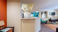 This well-appointed 2-bedroom, 2-bathroom single-floor residence offers a thoughtfully designed open-concept layout that seamlessly connects the main living areas. The entry foyer welcomes you with tile flooring and convenient access to an in-unit laundry area complete with a full-size washer and dryer. The kitchen is efficiently laid out with white cabinetry, light countertops, and stainless steel appliances including a range, over-the-range microwave, refrigerator, and dishwasher, all set over durable hardwood-style flooring. A peninsula counter opens the kitchen to the adjoining living and dining spaces. The dining area features a bold teal accent wall, patio door access, and abundant natural light. The spacious living room offers crown molding, a large window, and hardwood-style flooring throughout. Both bedrooms are carpeted, bathed in natural light from generous windows, and each features a ceiling fan and accent wall in a soft green tone. The bathrooms are clean and functional with light wood-style flooring, white vanities, and ample mirror space. This residence combines practical amenities with a vibrant, welcoming aesthetic throughout.