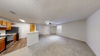 This single-floor, 2-bedroom, 2-bathroom residence in Birmingham, Alabama offers a well-organized layout designed for comfortable everyday living. The open living area features light wood-look flooring and a ceiling fan with light fixture, creating a bright and airy atmosphere. A large window allows natural light to fill the space, and the room flows seamlessly into the dining area and kitchen. The galley-style kitchen is equipped with warm honey-toned cabinetry, white countertops, a stainless steel refrigerator, electric range, and dishwasher, along with a double-basin sink and ample storage throughout. A dedicated closet at the end of the kitchen provides additional utility space. The primary bedroom is generously sized, featuring plush carpeting, a large window with exterior views, a closet, and direct access to one of the two bathrooms. The second bedroom is also carpeted and filled with natural light. Both bathrooms are consistently appointed with tiled tub-shower combinations, mirrors, and classic white fixtures. Throughout the home, textured ceilings, clean neutral walls, and wood-look or carpeted floors maintain a cohesive and practical aesthetic suited to a variety of lifestyles.
