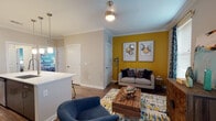 This thoughtfully designed single-floor residence showcases a blend of modern finishes and bold, expressive interior design. The living area makes an immediate impression with its striking mustard yellow accent wall, crown molding, hardwood-style flooring, and a ceiling fan with brushed nickel detailing. Natural light filters in through a window dressed with patterned drapes, creating a warm and inviting atmosphere.

The kitchen is outfitted with rich dark-toned cabinetry, white quartz countertops, a subtle tile backsplash, and a full suite of stainless steel appliances, including a refrigerator, range, and over-the-range microwave — a practical and visually cohesive space.

The primary bedroom features a deep navy accent wall adorned with a palm tree canvas, warm wood nightstands, plush carpeting, and ample natural light from a large window with blinds and curtains. The second bedroom carries a complementary teal accent wall with vibrant artwork, carpeted flooring, and generous closet access.

Both bathrooms are finished with wood-look flooring, floating dark vanities, white quartz countertops, and large mirrors. One bathroom includes a soaking tub with full tile surround, while the other features a spacious walk-in shower layout. Together, these rooms reflect a cohesive, contemporary design sensibility throughout the home.