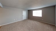This single-floor residence offers a well-organized layout with a variety of functional spaces throughout. The living area is generously sized, featuring neutral-toned carpet, a textured ceiling, and a large window that allows natural light to fill the room, creating a bright and welcoming atmosphere. Adjacent to the living area is a defined space with tile flooring, ideal for a dining area.

The galley-style kitchen is efficiently designed with rich, dark wood cabinetry running along both walls, granite-look countertops, a stainless steel double sink, and a white electric range with overhead ventilation. Tile flooring and a door at the end of the kitchen add practicality to the space.

The residence includes multiple carpeted bedrooms, each featuring neutral wall tones, blinds-covered windows for natural light and privacy, and ceiling-mounted light fixtures. The primary bedroom offers the added convenience of a private en-suite bathroom with a vanity and walk-in shower, as well as direct hallway access.

Two full bathrooms serve the home. One features a tub-shower combination with a curtain rod, a toilet, and a dark wood vanity with tile flooring. The second is a compact bathroom with a stand-up shower unit. Both bathrooms are finished in clean, neutral tones throughout.