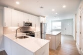 This two-story home in Manorville, NY offers a thoughtfully designed layout with contemporary finishes throughout. The main level centers around an open-concept kitchen and living area, where light hardwood flooring flows seamlessly underfoot. The kitchen is well-appointed with crisp white shaker cabinetry, a white quartz peninsula and island providing generous counter space, a subway tile backsplash, and a full suite of stainless steel appliances including a gas range, built-in microwave, and French door refrigerator. Recessed lighting illuminates the space, while a large window and French doors in the adjacent living area invite abundant natural light and provide direct outdoor access to the surrounding green landscape.

A half bath on the main level features a white vanity with quartz countertop and clean, neutral finishes. Upper-level bedrooms are carpeted and receive natural light through well-placed windows. Bathrooms are finished with white vanities, quartz countertops, and a tub-shower combination clad in large-format marble-look tile with polished chrome fixtures. Additional rooms with hardwood flooring offer flexible use options throughout this move-in-ready home.