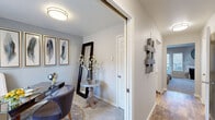 This two-floor residence offers a thoughtfully designed layout with a neutral, contemporary aesthetic throughout. The living room serves as a central gathering space, anchored by a white-mantled fireplace and complemented by a sliding glass door that opens to a private balcony, allowing natural light and outdoor views to enhance the room's welcoming ambiance. Soft carpet flooring and a ceiling fan contribute to a comfortable atmosphere.

The kitchen is outfitted with white shaker-style cabinetry, stainless steel appliances including a refrigerator, microwave, and electric range, and a white quartz peninsula countertop that doubles as a breakfast bar with space for seating. A versatile den or home office off the hallway features carpet flooring and a large wall opening, making it a functional secondary space.

The bedrooms offer plush carpet, natural light through well-dressed windows with blinds and drape panels, and closet storage. The primary bedroom includes a mirrored sliding closet, while an additional bedroom features a distinct accent wall with blue-gray tones. The full bathroom is finished with wood-look vinyl flooring, a white vanity with undermount sink, and a tub-shower combination.