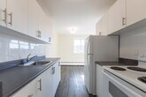 Located at 55 McMurchy Ave N in Brampton, Ontario, this 2-bedroom, 1-bathroom unit offers a practical and well-designed layout across a single floor. The galley-style kitchen is efficiently organized with white cabinetry, dark countertops, a stainless steel sink, and white appliances including a refrigerator and electric range. It flows seamlessly into a combined living and dining area, which is bright and open, featuring light-toned laminate flooring and warm neutral walls that create a clean, welcoming atmosphere. Both bedrooms are comfortably sized, each featuring the same laminate flooring, neutral walls, and sliding windows that bring in natural light and views of the surrounding neighbourhood. Baseboard heaters are present in each bedroom. The bathroom is finished with white tile surrounding a full soaker tub and shower combination, maintaining a crisp, clean aesthetic. A standout feature of this unit is the private balcony, accessible from the living area, which offers open views of the Brampton cityscape, mature trees, and neighbouring buildings under an expansive sky. The unit's consistent flooring, neutral palette, and functional layout make it a practical and comfortable urban residence.