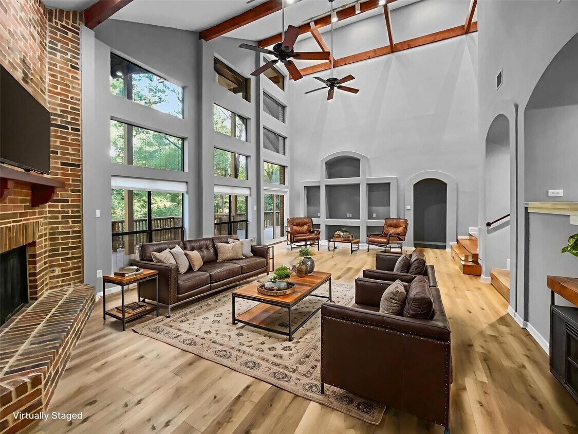 Una impresionante sala de estar con un alto techo abovedado, suelo de vinilo de lujo, una acogedora chimenea de gas de ladrillo y una - 1314 Creekwood Dr