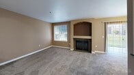 Located in Puyallup, WA, this single-floor, 2-bedroom, 1-bathroom home offers a well-organized layout across a comfortably sized floor plan. The open-concept living and dining area serves as the heart of the home, featuring plush carpeting, warm neutral-toned walls, and a standout arched fireplace nook that adds architectural character. Natural light filters in through windows with outdoor views, enhancing the welcoming ambiance. The kitchen is efficiently designed with warm wood cabinetry, dark countertops, a peninsula breakfast bar, tile flooring, and black appliances including a range, microwave, refrigerator, and dishwasher. A hallway connects the main living areas to the private spaces, which include two carpeted bedrooms, each featuring windows that bring in natural light and baseboard heating. Three closets provide ample storage throughout the home. A dedicated laundry area adds everyday convenience. The bathroom serves the two bedrooms efficiently. Neutral tones and consistent flooring choices throughout create a cohesive and practical living environment suitable for a range of lifestyles.