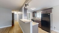This efficiently designed 2-bedroom, 1-bathroom single-story home offers a clean, modern aesthetic throughout. Light gray walls and warm luxury vinyl plank flooring flow seamlessly across all rooms, creating a cohesive and contemporary feel.

The open-concept kitchen is a standout feature, equipped with dark shaker-style cabinetry, granite countertops, black stainless steel appliances including a gas range, microwave, dishwasher, and refrigerator, plus a peninsula with track lighting overhead. The kitchen connects directly to the dining area, which features a stylish chandelier and a window with natural light. The living room provides a welcoming entry point with a large window overlooking the exterior.

The primary bedroom is a comfortable, well-proportioned space with a ceiling fan, natural light from a window, and direct closet access. The second bedroom features dual windows on adjacent walls, filling the room with ample daylight. Both bedrooms benefit from the warm flooring and neutral palette found throughout the home.

The bathroom is finished with classic white subway tile surround in the tub/shower, accented by a metallic border tile and a natural light window. An in-unit laundry room with a full-size washer and dryer adds everyday convenience. Two closets provide practical storage solutions throughout the home.