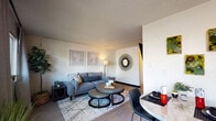 Located at 1920 NE Terre View Drive in Pullman, Washington, this single-floor residence offers a well-organized and stylishly appointed layout. The open-concept living and dining area serves as the heart of the unit, where light-toned walls and wood-style flooring create a clean, contemporary feel. The living room provides a comfortable and functional space, accented by decorative wall art and soft lighting. Adjacent to it, the dining area features a round marble-top table paired with sleek black chairs, complemented by framed botanical wall art that adds a touch of greenery to the space. The galley-style kitchen is efficiently designed with gray cabinetry, dark countertops, and stainless steel appliances, including an electric range and dishwasher. A window at the end of the kitchen allows natural light to brighten the workspace. The bedroom offers a cozy retreat with wood-style flooring, textured ceiling, and ample wall space for personalization, along with room for a study desk. Two bathrooms are present — one featuring dark countertops and a tub-shower combination, and the other finished in lighter tones with a window for natural light. Together, these spaces form a practical and attractively designed unit well-suited for comfortable everyday living.